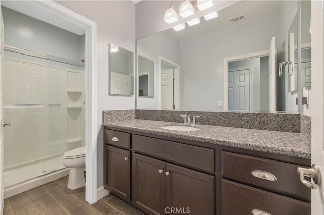 bathroom featuring an enclosed shower, vanity, and toilet