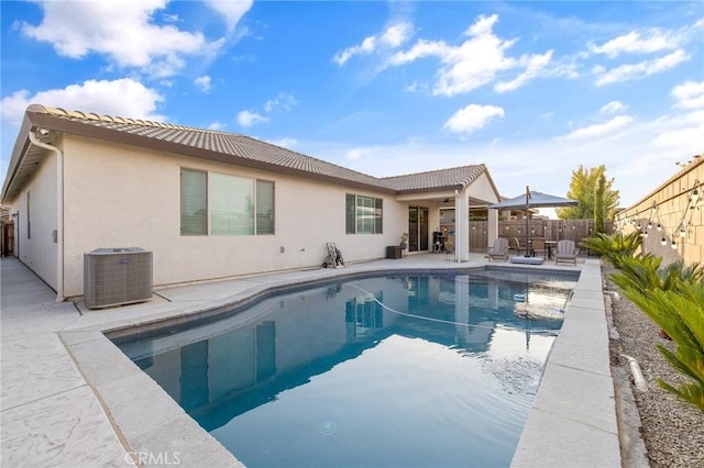 rear view of property featuring a patio, central air condition unit, and a fenced in pool