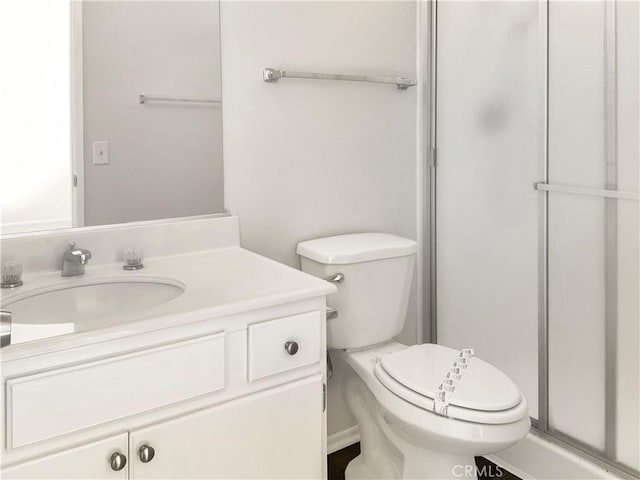 bathroom featuring a shower with door, vanity, and toilet