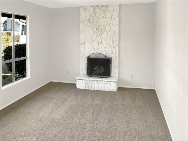 unfurnished living room with a stone fireplace and carpet