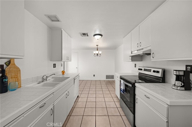 kitchen featuring under cabinet range hood, visible vents, stainless steel electric stove, and tile counters