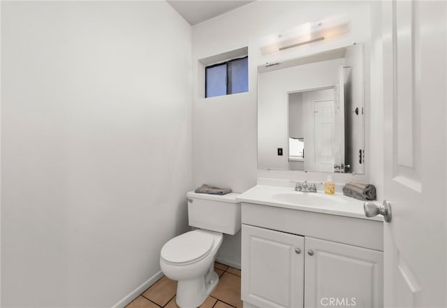 half bathroom featuring toilet, vanity, baseboards, and tile patterned floors