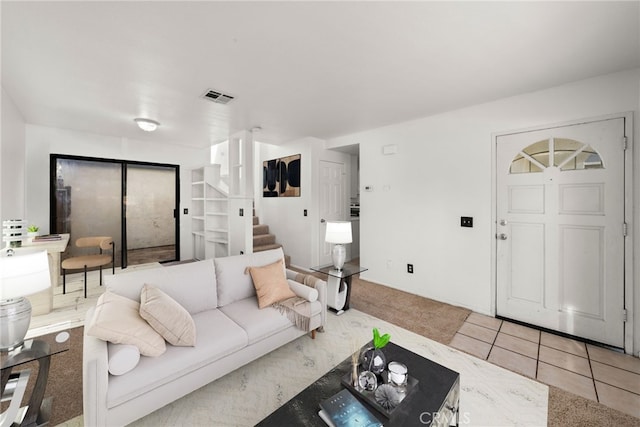 tiled living room featuring stairs and visible vents