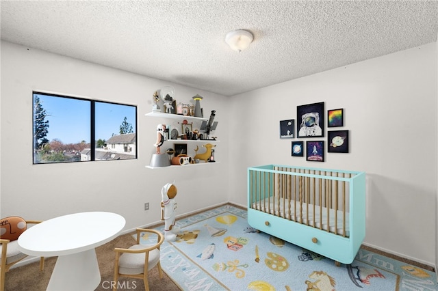 bedroom with baseboards, carpet flooring, a crib, and a textured ceiling