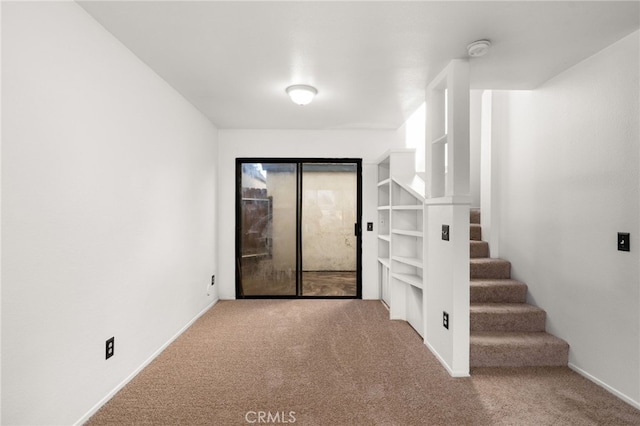 carpeted spare room with baseboards and stairs