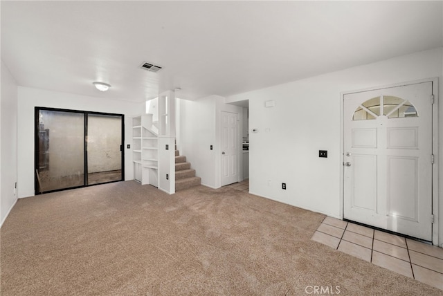 carpeted entryway with visible vents, stairway, and tile patterned floors