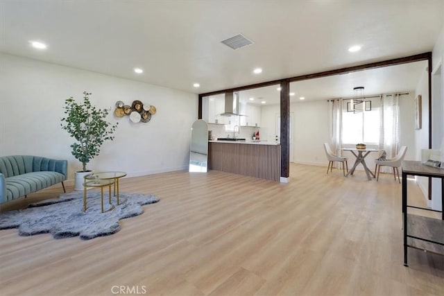 living room featuring sink, light hardwood / wood-style floors, and beamed ceiling