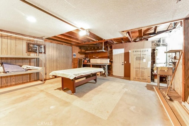 recreation room with wooden walls, pool table, water heater, a workshop area, and concrete floors