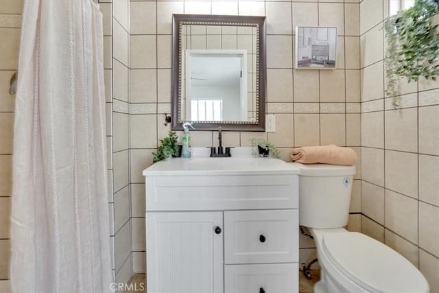 bathroom featuring toilet, vanity, and tile walls