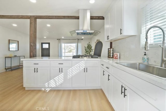 kitchen featuring white cabinetry, island exhaust hood, light wood-type flooring, and kitchen peninsula