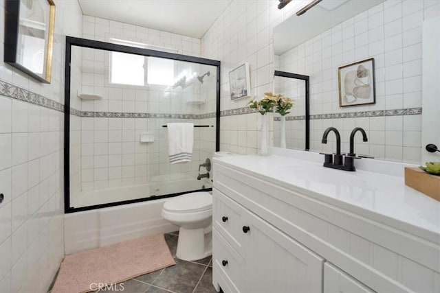 full bathroom with tile walls, enclosed tub / shower combo, tile patterned floors, and toilet