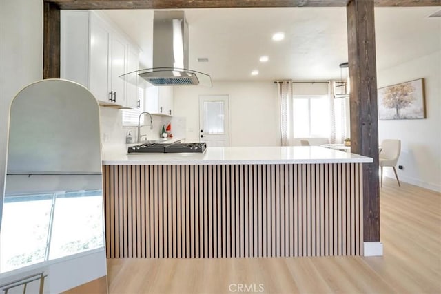 kitchen featuring white cabinetry, light wood-type flooring, island exhaust hood, decorative backsplash, and black gas stovetop