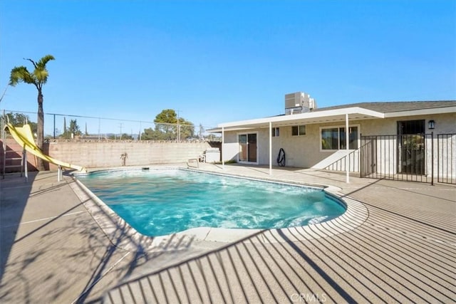 view of swimming pool featuring cooling unit, a water slide, and a patio