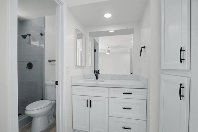 bathroom featuring toilet, hardwood / wood-style flooring, walk in shower, ceiling fan, and vanity