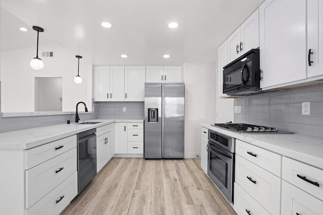 kitchen featuring backsplash, white cabinets, black appliances, and hanging light fixtures