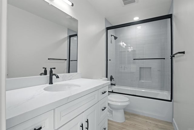 full bathroom featuring toilet, combined bath / shower with glass door, vanity, and hardwood / wood-style floors