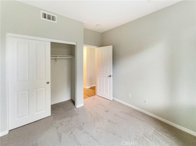 unfurnished bedroom featuring light colored carpet and a closet