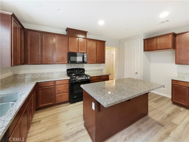 kitchen featuring light hardwood / wood-style flooring, light stone counters, and black appliances