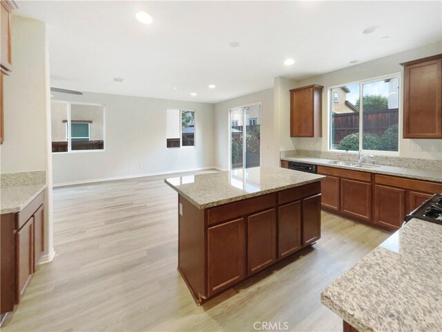 kitchen featuring sink, a center island, light hardwood / wood-style floors, and light stone countertops