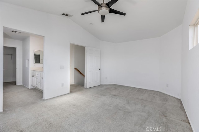 unfurnished bedroom with vaulted ceiling, connected bathroom, ceiling fan, and light colored carpet