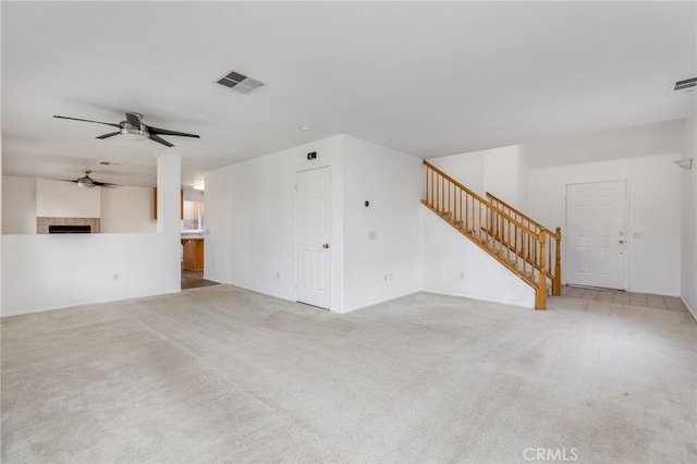 unfurnished living room with a tile fireplace, light carpet, and ceiling fan