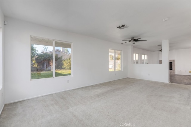 interior space featuring a tile fireplace, ceiling fan, and light colored carpet