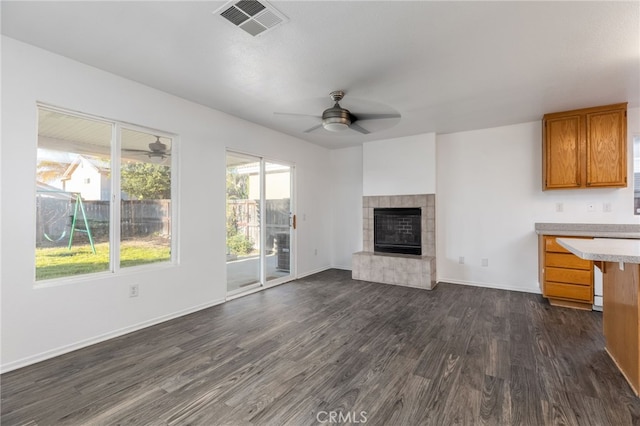 unfurnished living room featuring a fireplace, dark wood-type flooring, and ceiling fan