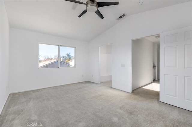 empty room with ceiling fan, vaulted ceiling, and light colored carpet