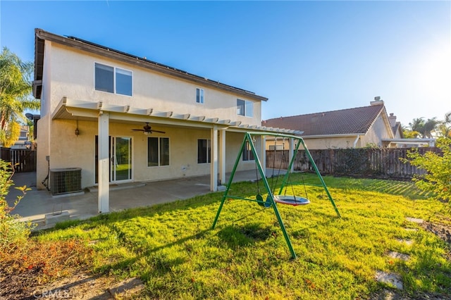 rear view of property featuring a lawn, central AC, a playground, and a patio area