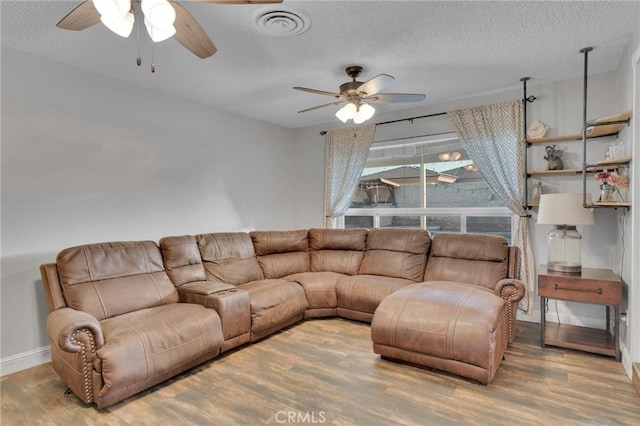 living room featuring a textured ceiling, ceiling fan, and wood-type flooring