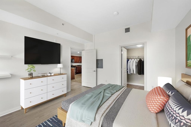 bedroom with a walk in closet, dark hardwood / wood-style flooring, and a closet