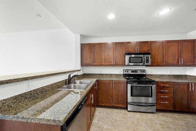 kitchen featuring stainless steel appliances, sink, and dark stone countertops