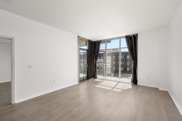 empty room with floor to ceiling windows and hardwood / wood-style floors