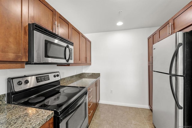 kitchen featuring stainless steel appliances, light tile patterned floors, and dark stone counters