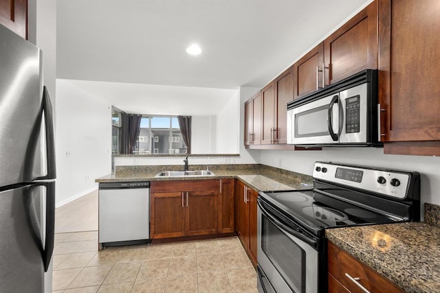 kitchen featuring stainless steel appliances, dark stone countertops, sink, and light tile patterned floors