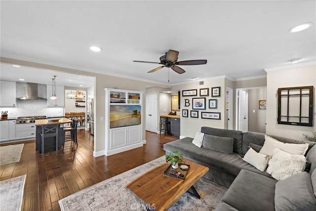 living room featuring ceiling fan, ornamental molding, and dark wood-type flooring