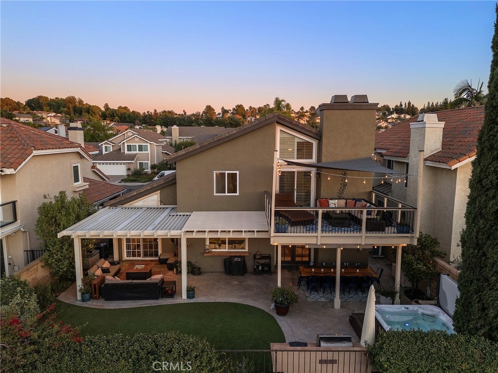 back house at dusk with an outdoor hangout area, a balcony, and a patio area