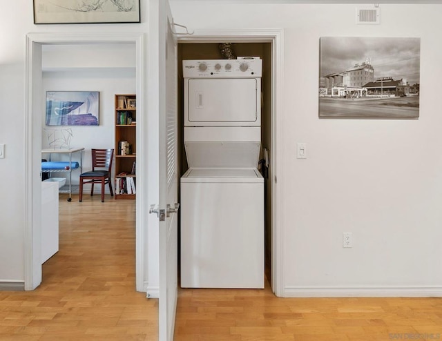 washroom featuring light hardwood / wood-style flooring and stacked washing maching and dryer