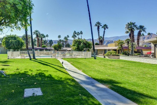 view of community with a swimming pool, a yard, and a mountain view