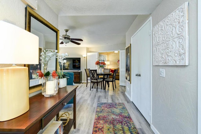 interior space with ceiling fan, a textured ceiling, and wood-type flooring