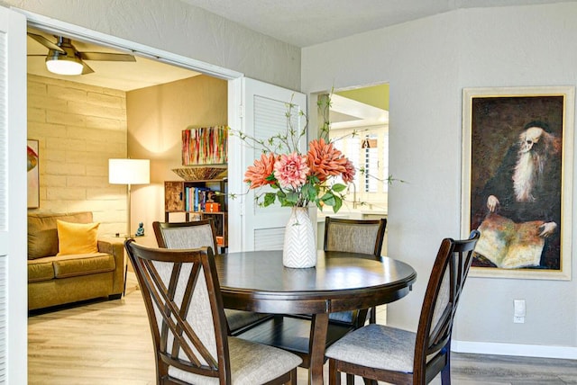 dining space with ceiling fan, light wood-type flooring, and lofted ceiling