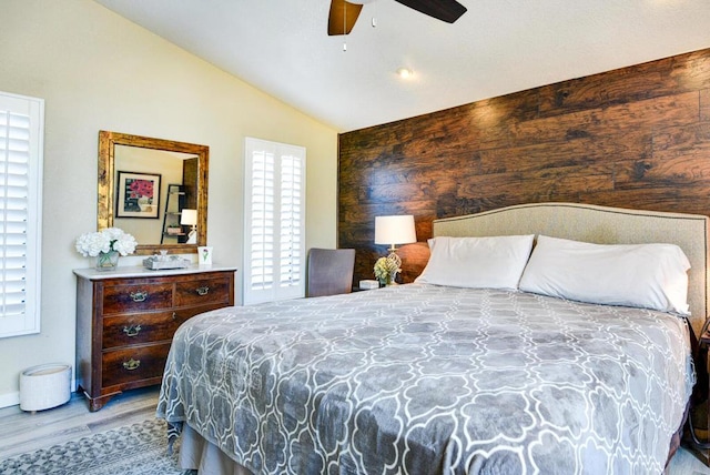 bedroom with ceiling fan, vaulted ceiling, multiple windows, and hardwood / wood-style flooring