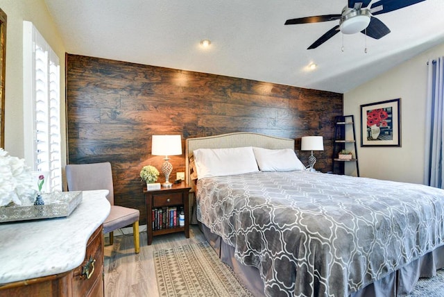 bedroom with lofted ceiling, wood-type flooring, wooden walls, and ceiling fan