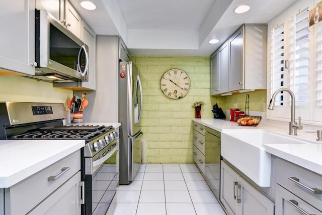 kitchen featuring sink, light tile patterned floors, gray cabinetry, and appliances with stainless steel finishes