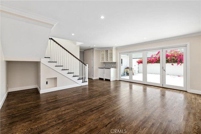 unfurnished living room with french doors, crown molding, and dark wood-type flooring