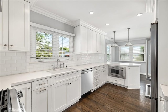 kitchen with sink, white cabinetry, kitchen peninsula, pendant lighting, and appliances with stainless steel finishes