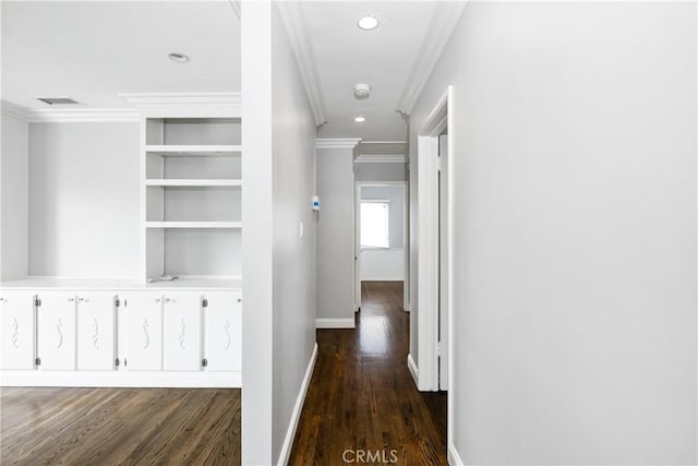 hallway with dark wood-type flooring, built in shelves, and crown molding