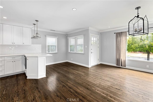 kitchen featuring white cabinetry, decorative backsplash, hanging light fixtures, crown molding, and dark wood-type flooring