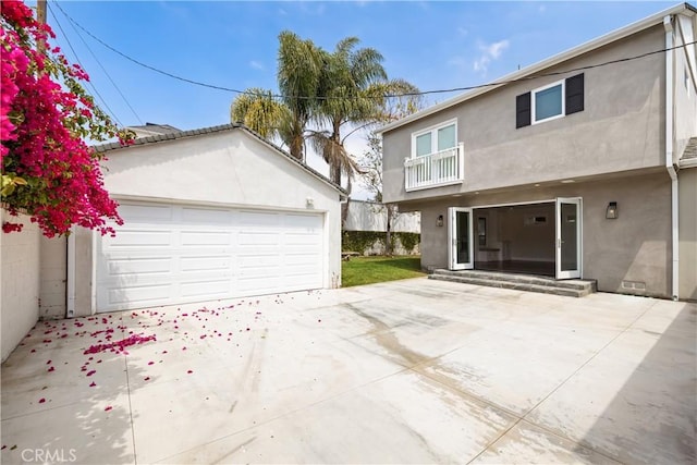 back of house with a balcony, a garage, and an outdoor structure