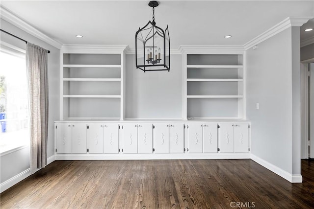 unfurnished dining area with an inviting chandelier, built in shelves, crown molding, and dark wood-type flooring